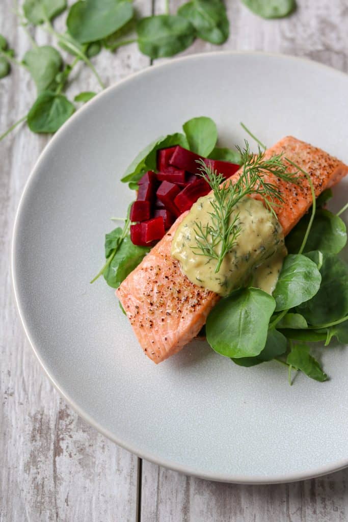 Salmon with mustard sauce, pickled beets and salad on a plate