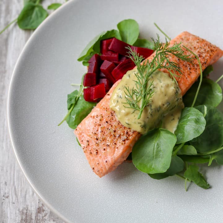 Salmon with mustard sauce, pickled beets and salad on a plate