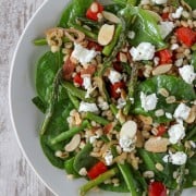 Asparagus, red pepper and spinach salad topped with goat cheese on a plate