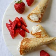 Krumkake filled with whipped cream and strawberries on a plate