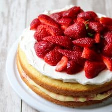 Strawberry cream cake topped with fresh strawberries on a plate