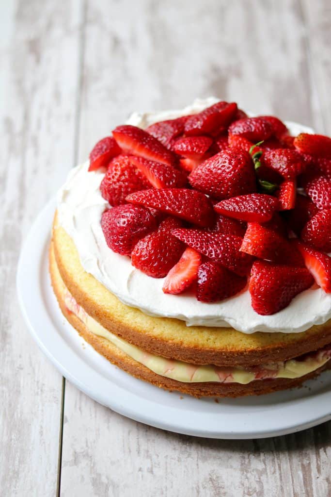 Strawberry cream cake topped with fresh strawberries on a plate