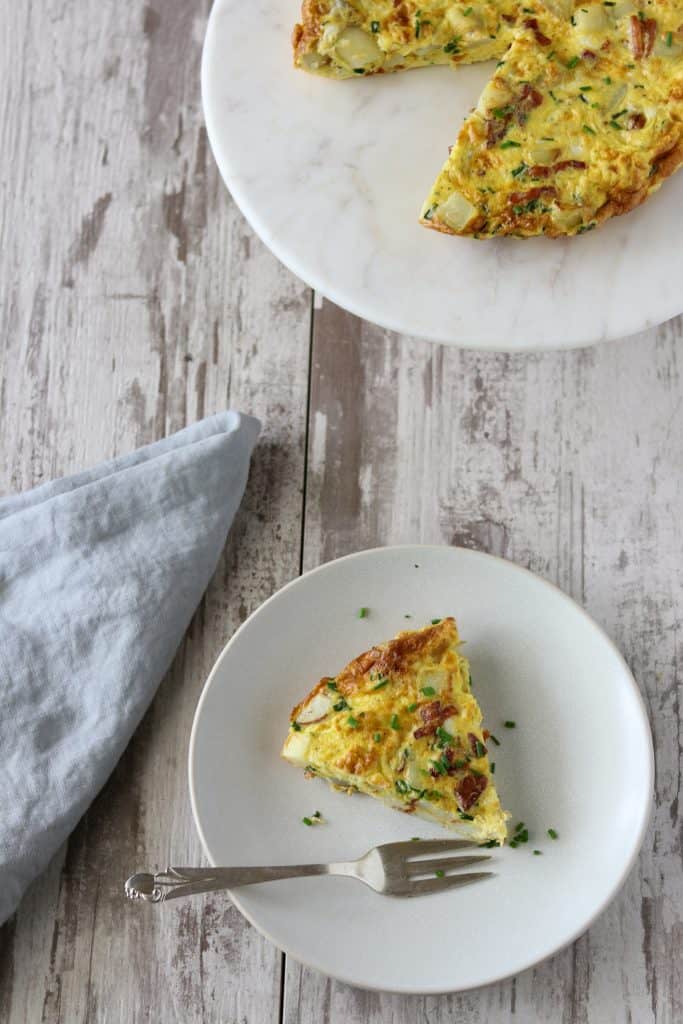 A slice of Danish egg cake on a plate next to a blue napkin