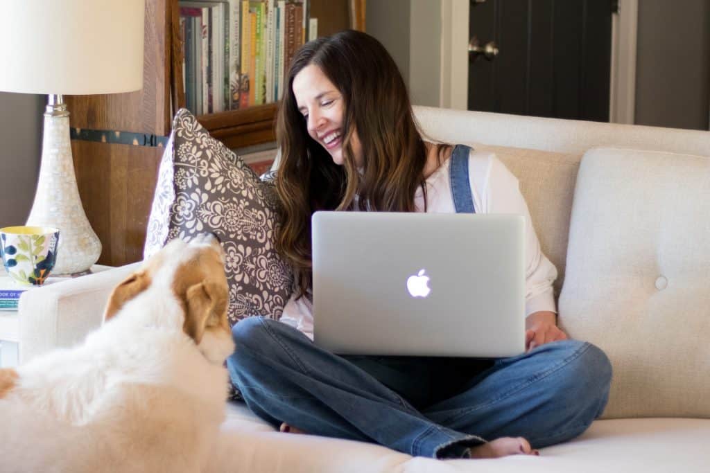 Kristi Bissell sitting on the couch working on her laptop with her dog