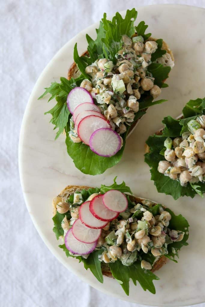 Open sandwiches with chickpea salad, radishes and lettuce on a plate