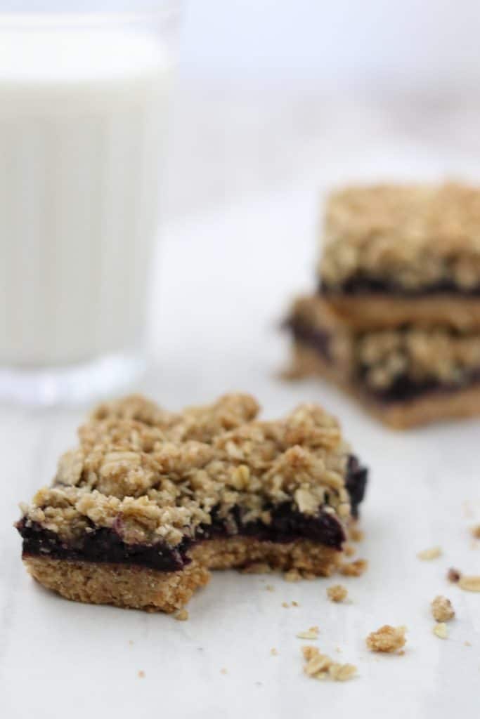 A close up of blueberry crumble bars with a glass of milk