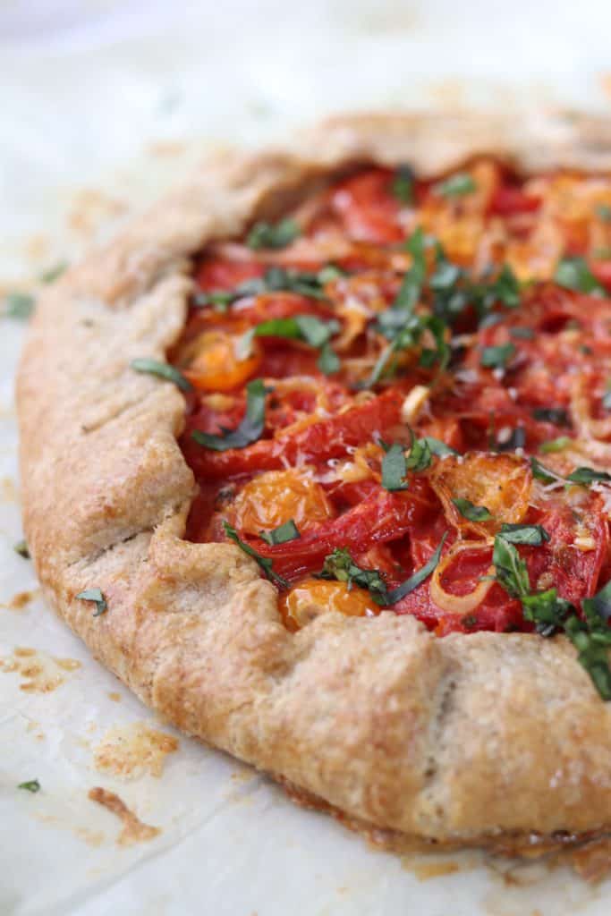 A close up of a rustic tomato tart topped with basil