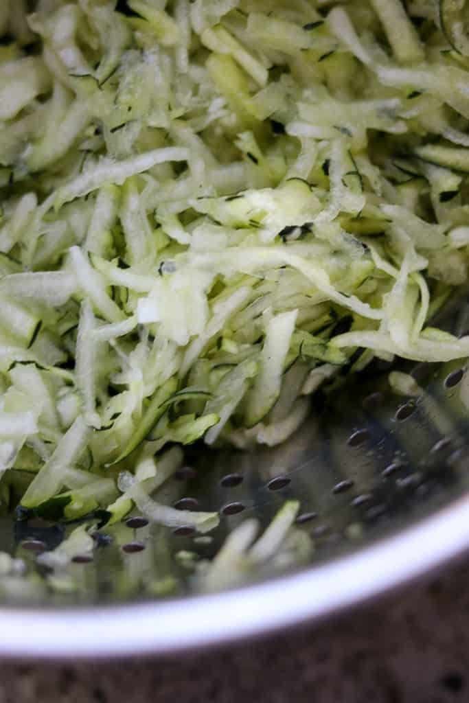 Shredded zucchini in a metal colander