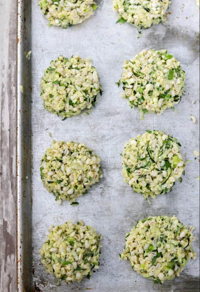 Uncooked zucchini barley cakes on a sheet pan