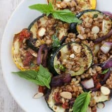 A plate of grilled summer squash salad topped with basil leaves