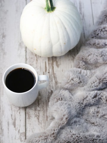 A blanket, pumpkin and a cup of coffee