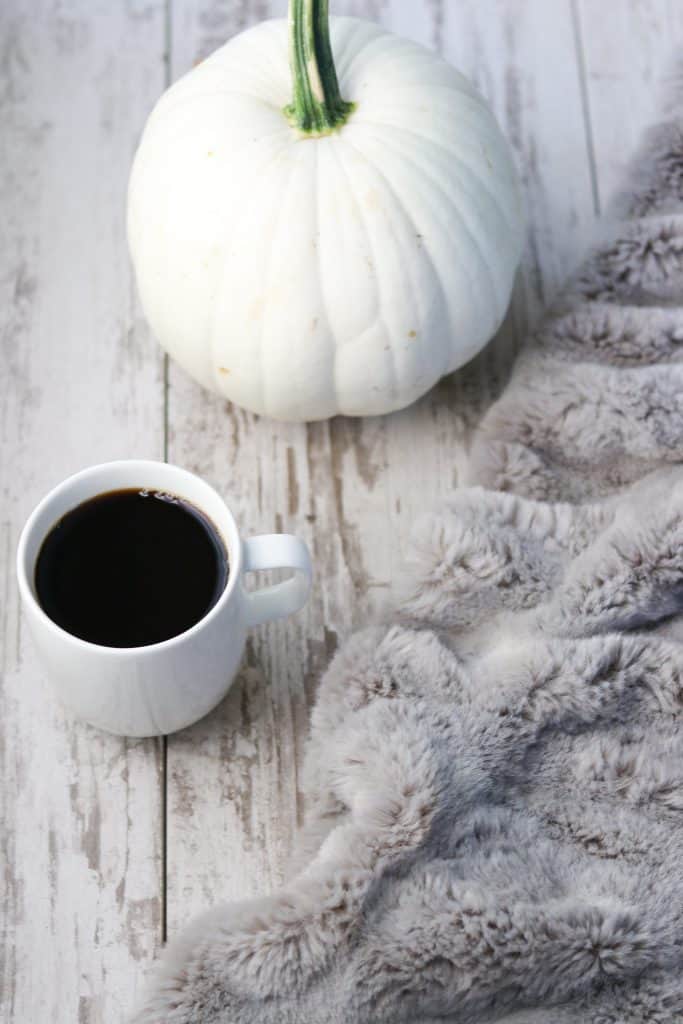 A blanket, pumpkin and a cup of coffee