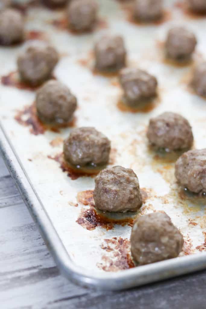 A close up of cooked meatballs on a sheet pan