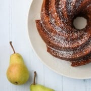 A pear cardamom bundt cake on a plate with two pears