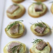 A close up of pickled herring bites topped with dill