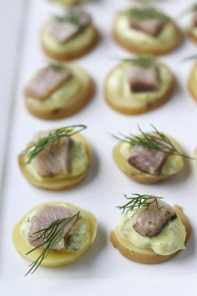 A close up of pickled herring bites topped with dill