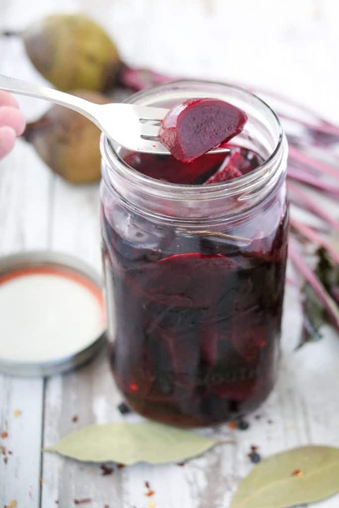 A jar filled with pickled beets and a fork