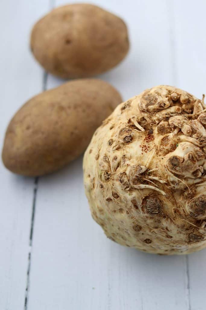 A celery root and potatoes on a wood surface