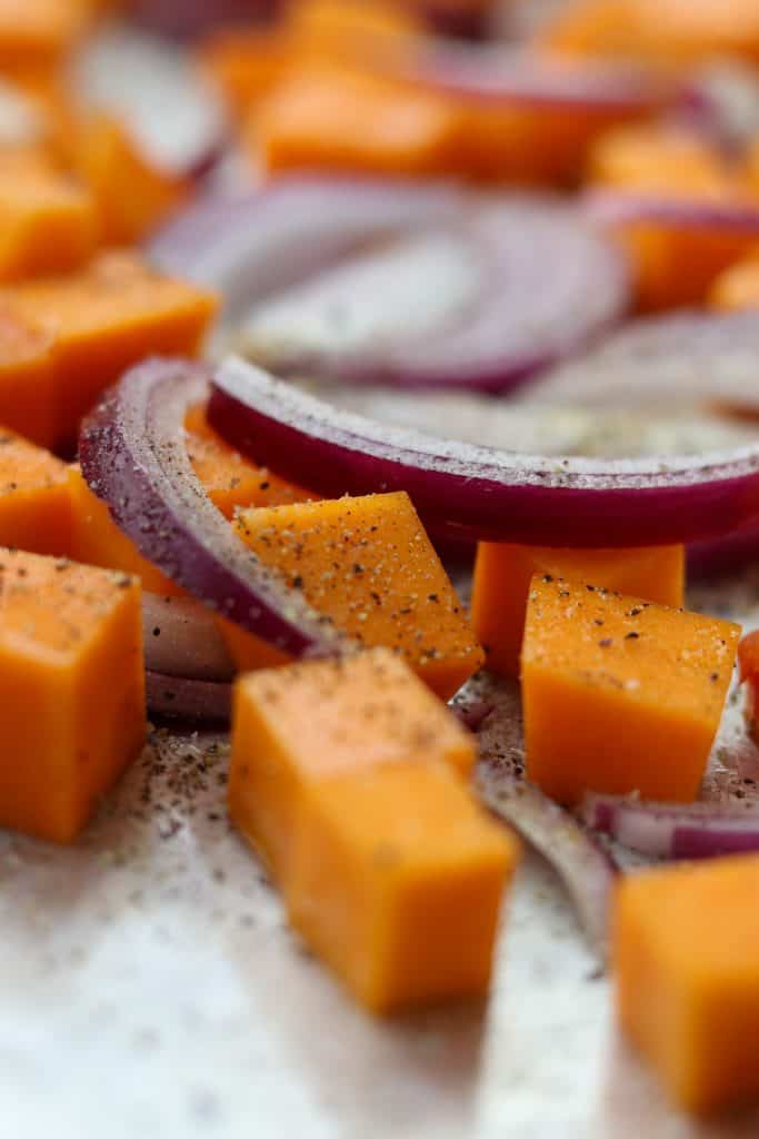 A close up of cubed squash and red onion slices