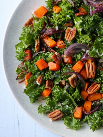 Kale salad with roasted butternut squash and pecans on a plate