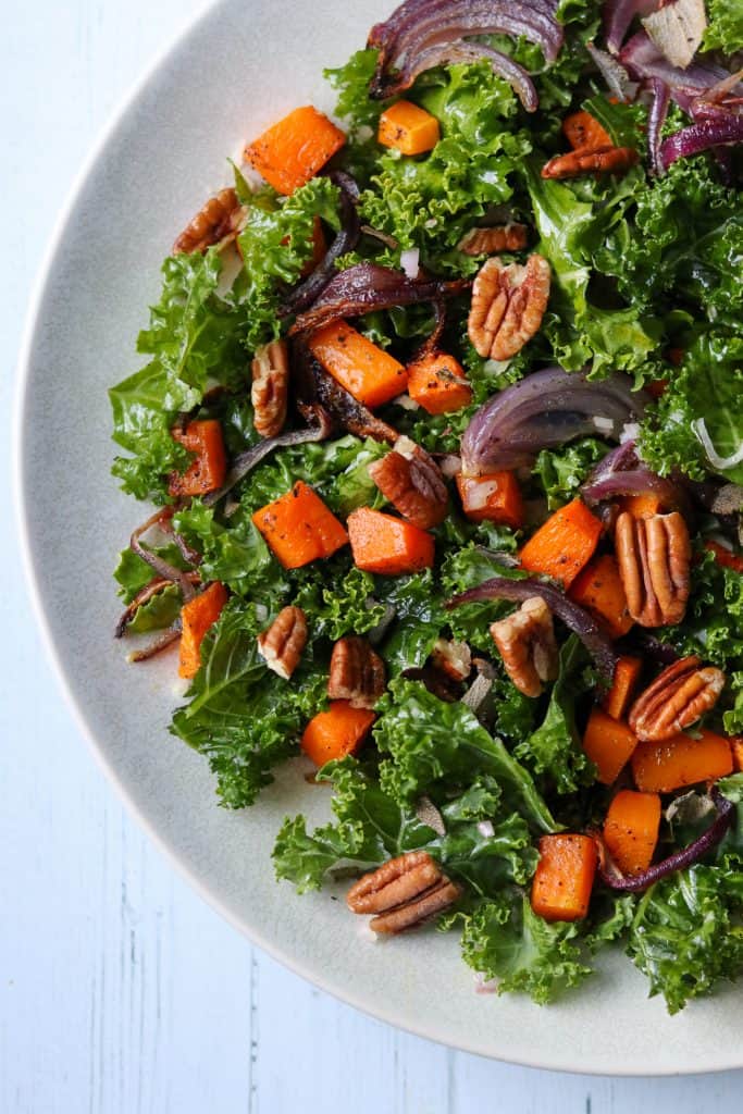 Kale salad with roasted butternut squash and pecans on a plate