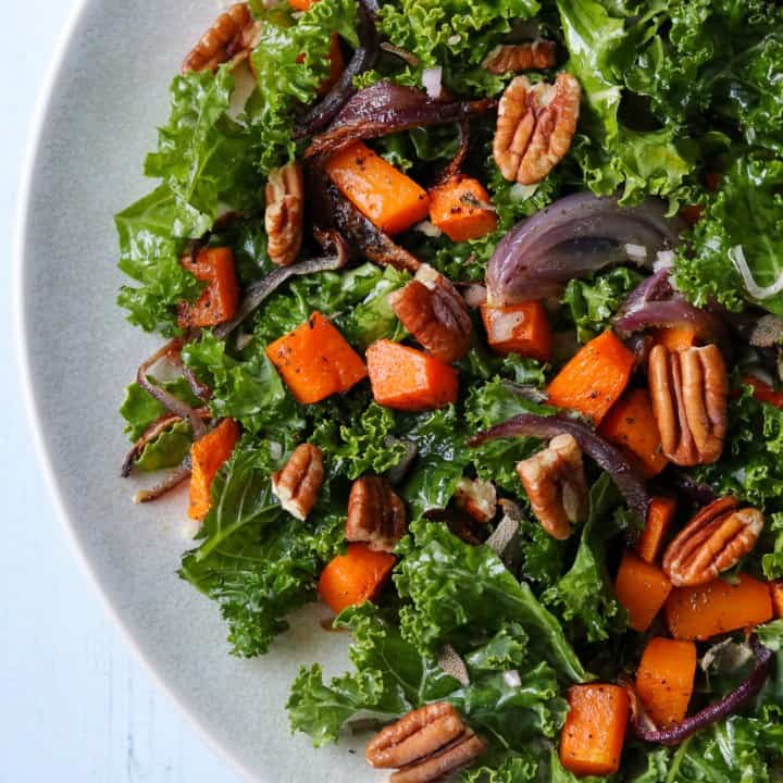 Kale salad with roasted butternut squash and pecans on a plate