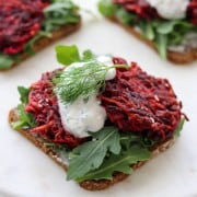 An open sandwich with beet and celery root cakes and creamy sauce on a plate