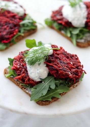 An open sandwich with beet and celery root cakes and creamy sauce on a plate