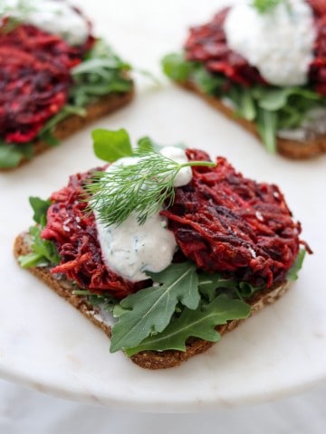 An open sandwich with beet and celery root cakes and creamy sauce on a plate