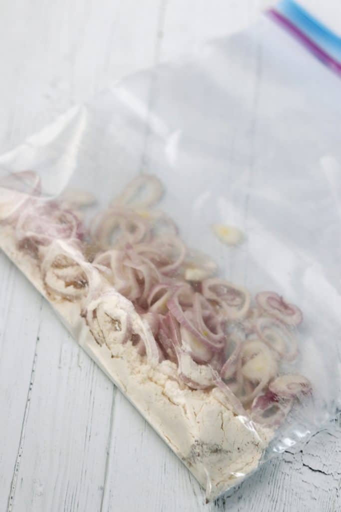 Shallots and flour in a plastic bag on a wooden surface