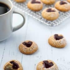 Raspberry heart cookies next to a cup of coffee