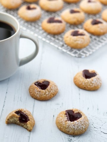 Raspberry heart cookies next to a cup of coffee