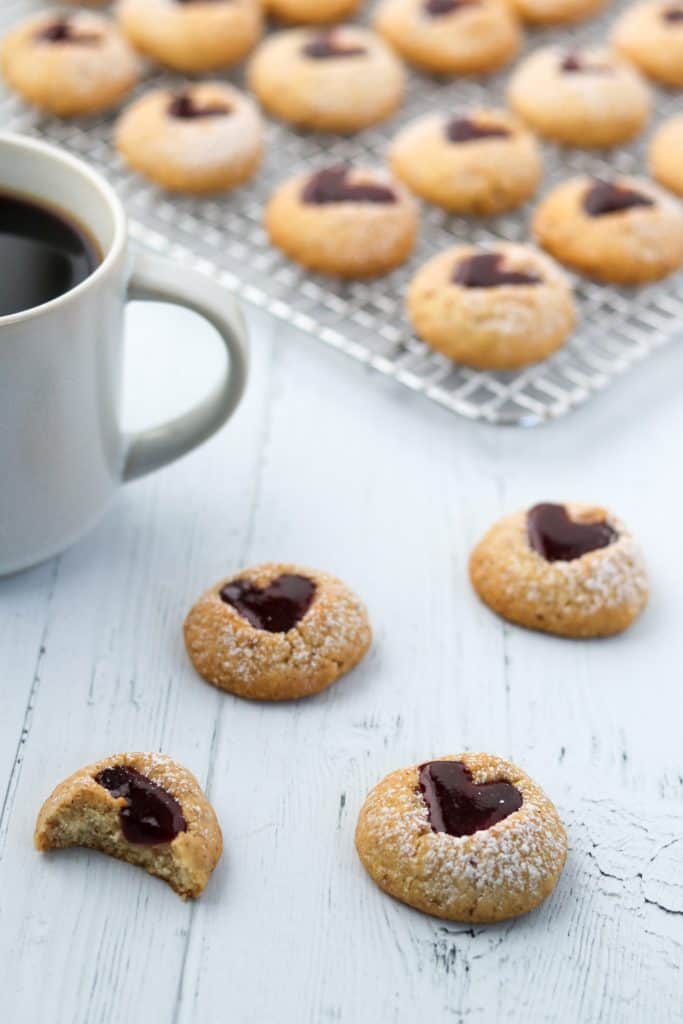 Raspberry heart cookies next to a cup of coffee