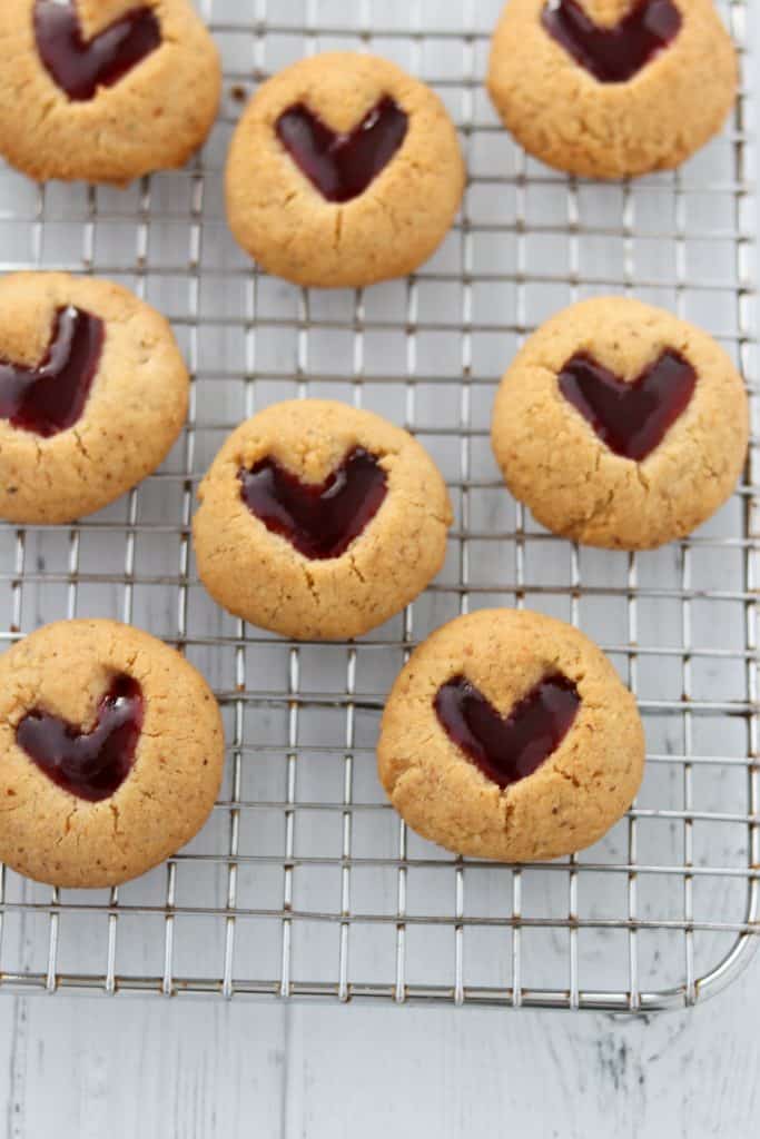 A close up of raspberry heart cookies on a cooling rack