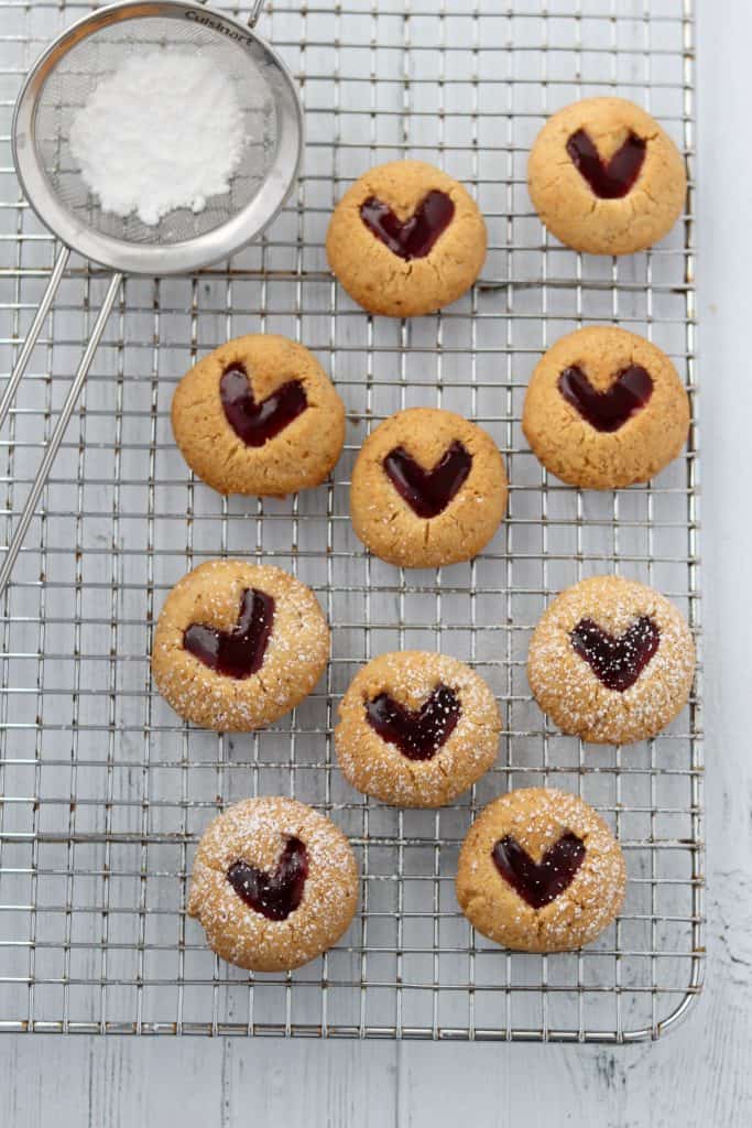 Raspberry heart cookies on a cooling rack with powdered sugar