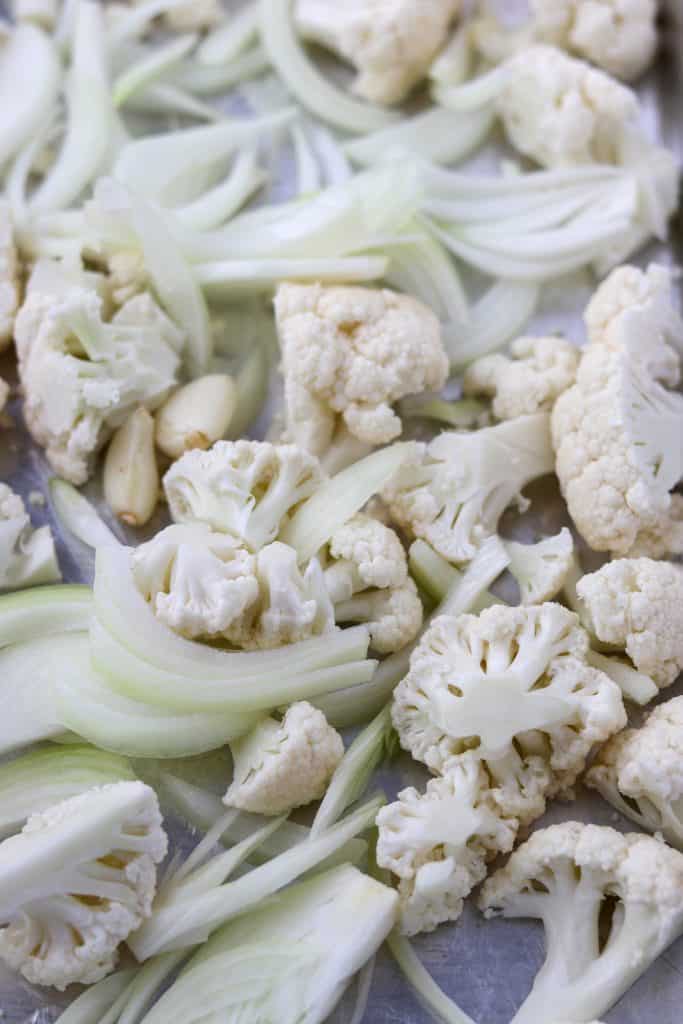 A close up of cauliflower florets, onions and garlic