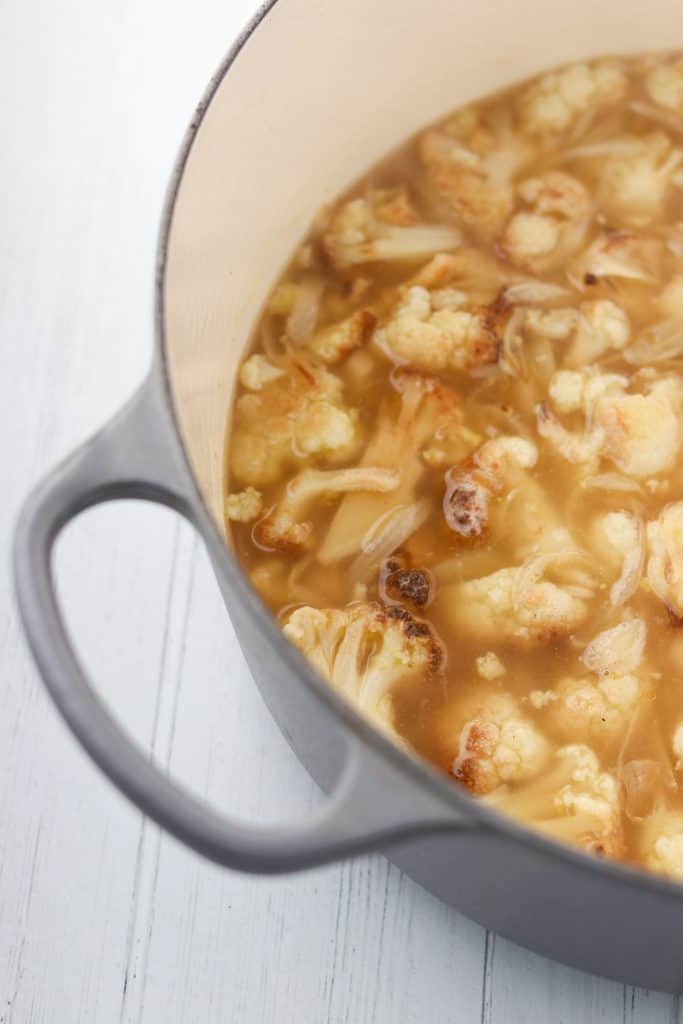 Cauliflower and broth in a pot on a wood surface