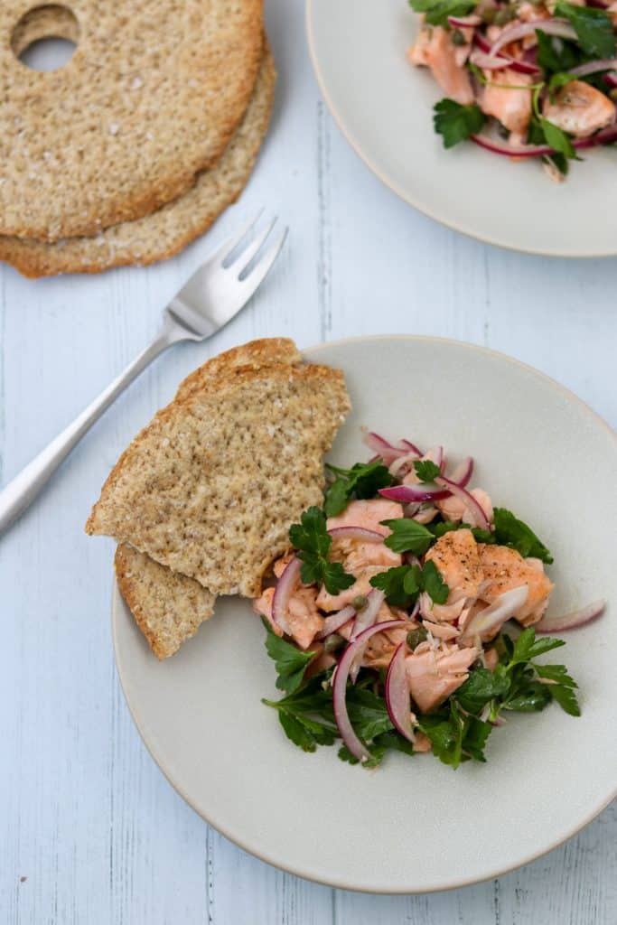 Salmon salad on a plate with crispbread next to a fork