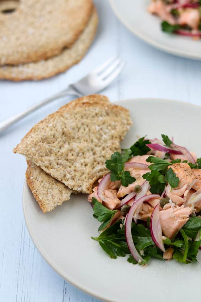 Salmon salad on a plate with crispbread next to a fork