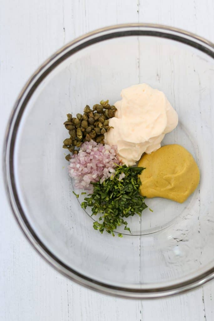 A bowl with mayonnaise, mustard, capers, shallots and herbs