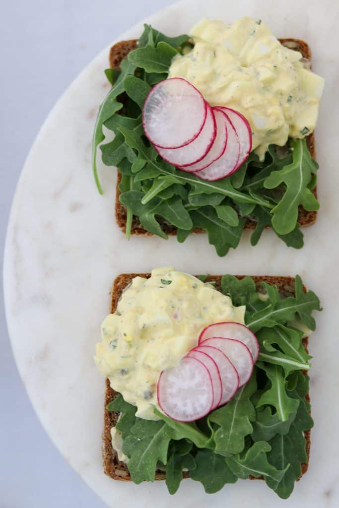 Open sandwiches with egg salad, radishes and lettuce on a plate