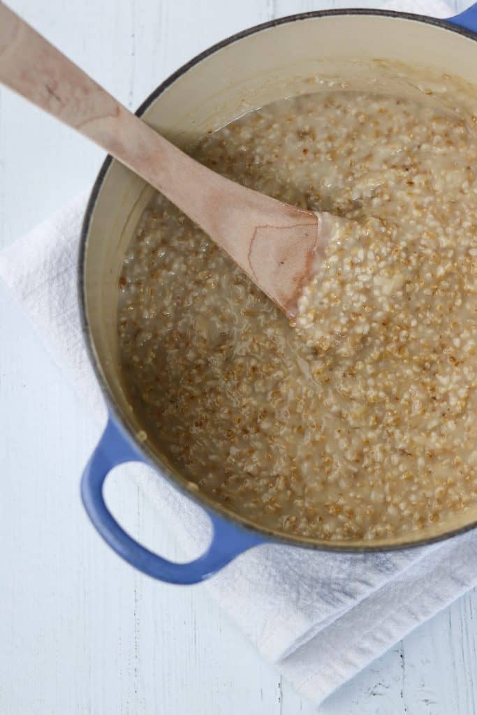 A pot of cooked oats with a wooden spoon