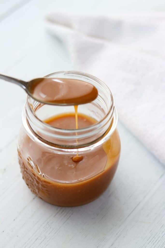 Caramel sauce in a jar with a spoon