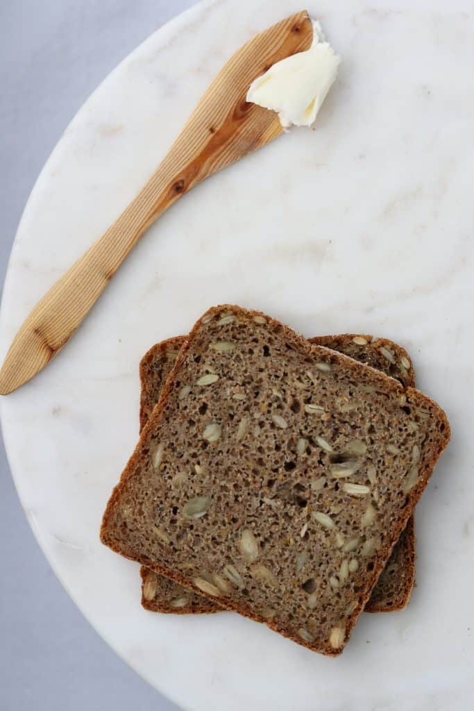 Rye bread on a plate with a wooden knife and butter