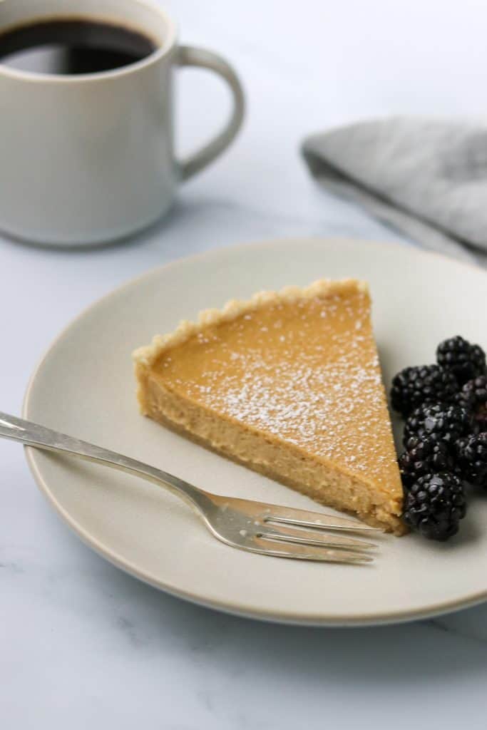 A slice of brown sugar skyr tart on a plate with blackberries and a fork