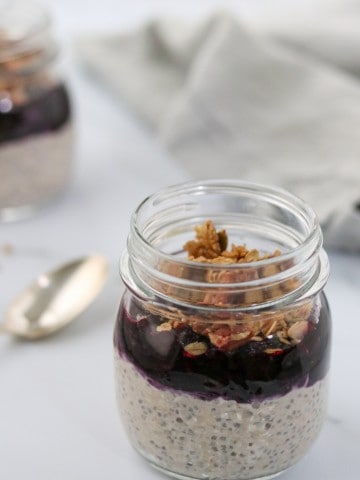 Overnight oats topped with blueberry and granola in a jar with a spoon