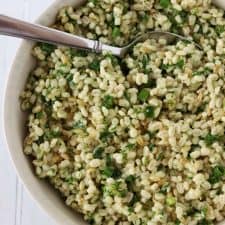 Barley salad with fresh herbs in a bowl with a spoon