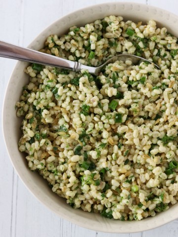 Barley salad with fresh herbs in a bowl with a spoon
