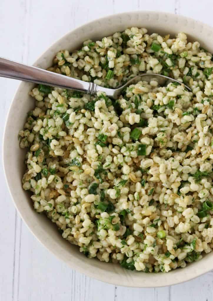 Barley salad with fresh herbs in a bowl with a spoon