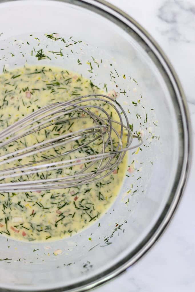 A bowl of salad dressing with a whisk